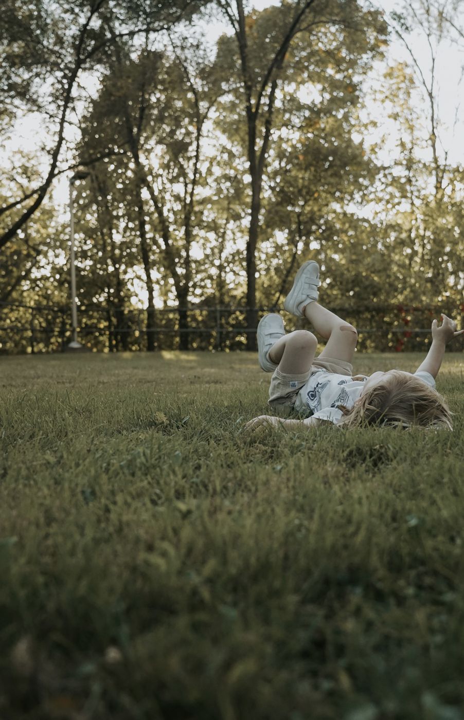 Child rolling happily in the grass with feet in the air