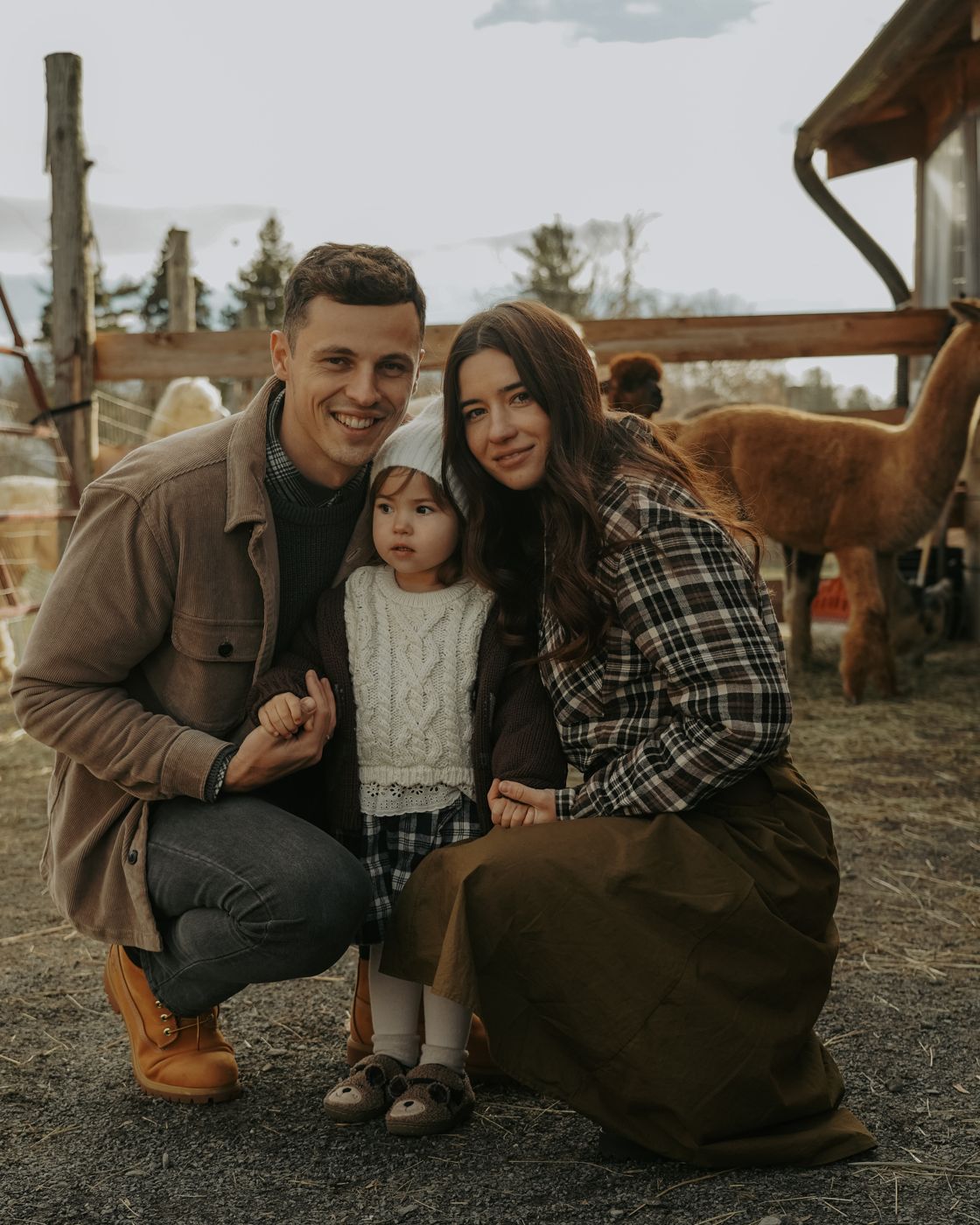 Family crouching together with their toddler at an alpaca farm