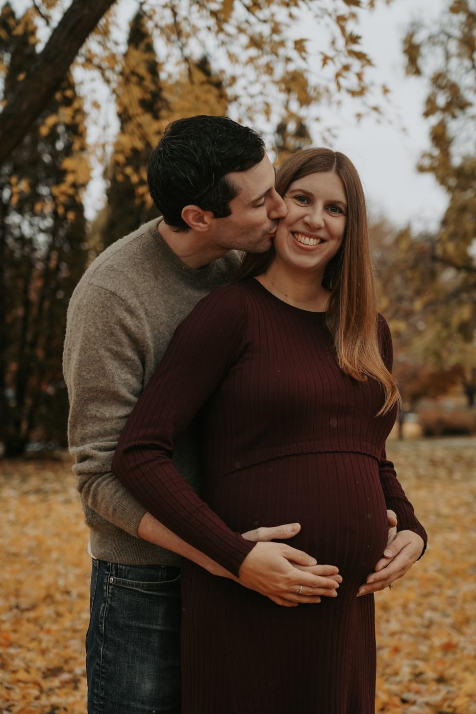 Partner kissing the mom-to-be on the cheek while holding her bump