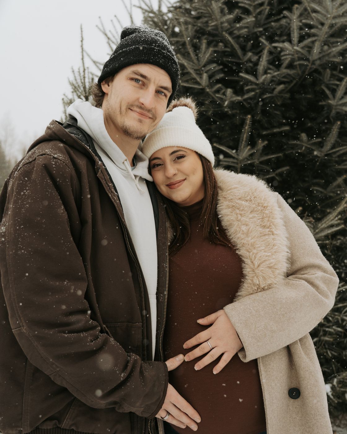 Mom-to-be leaning her head on her partner's shoulder in the snow