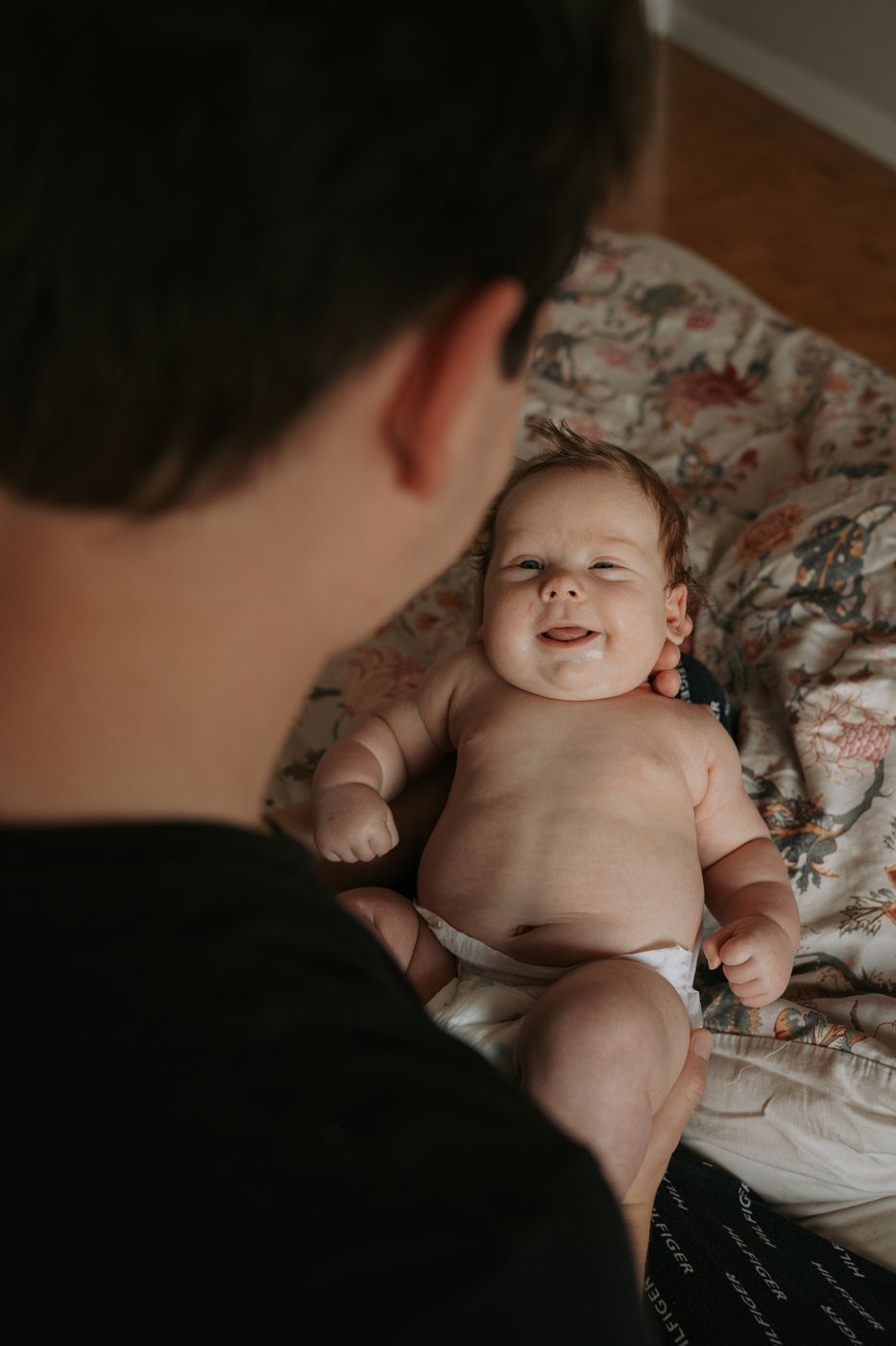 Smiling newborn looking up at dad on a floral blanket