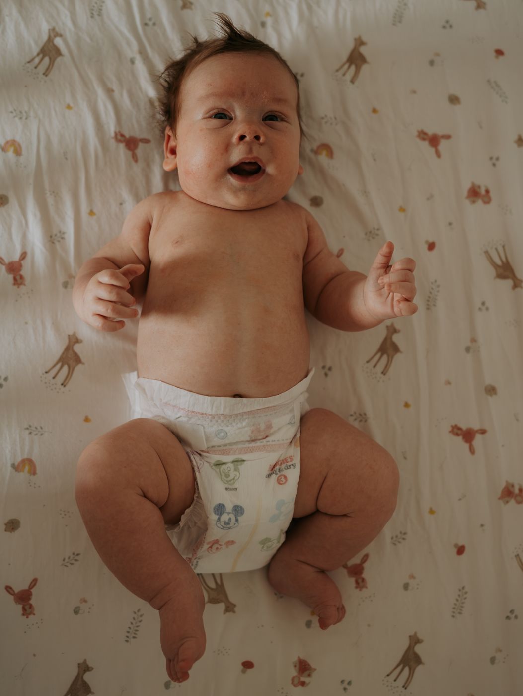 Happy baby on a deer-print crib sheet