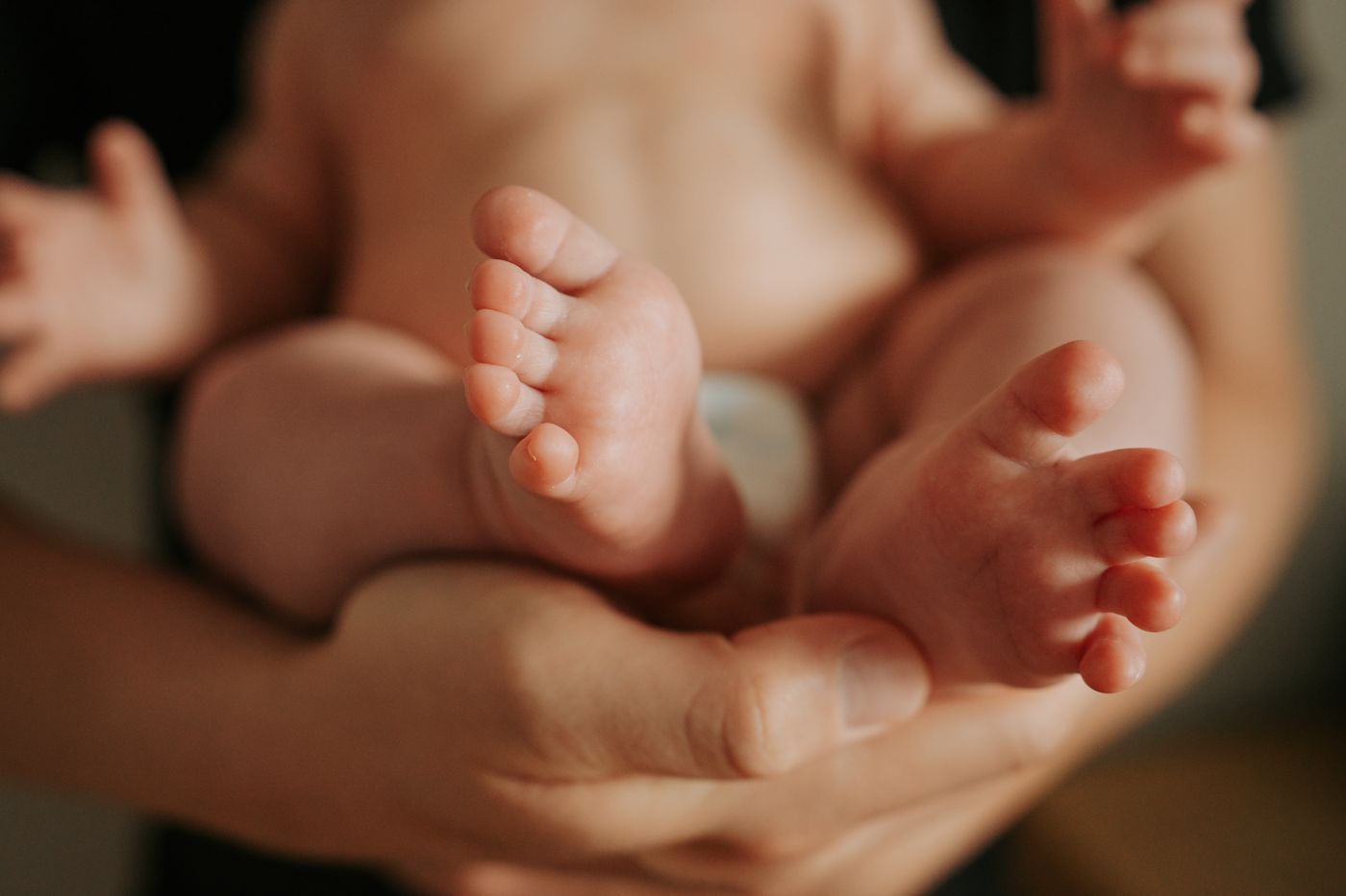 Tiny newborn feet cradled in a parent's hands