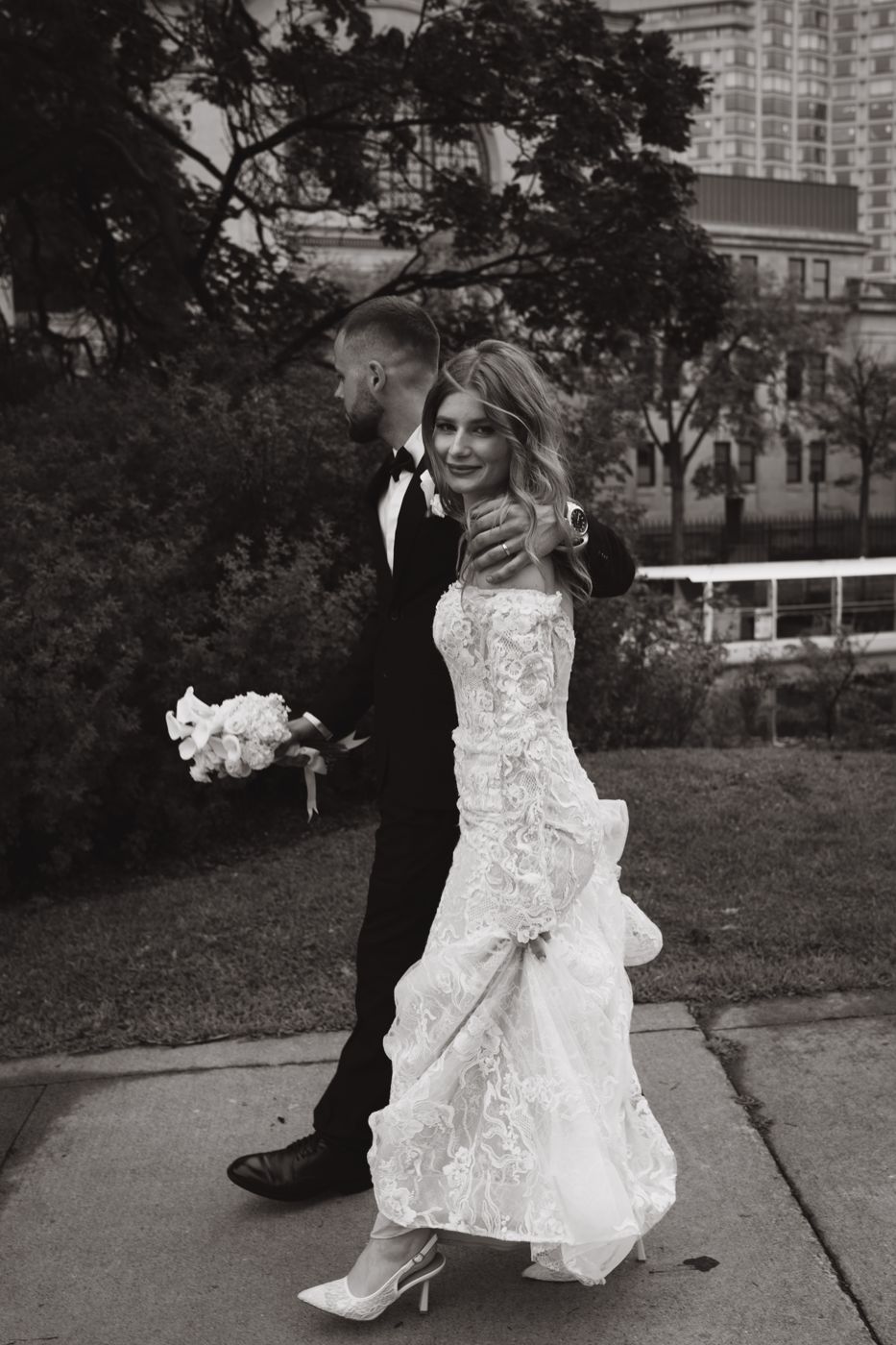 Black and white photo of a bride and groom walking through downtown Ottawa